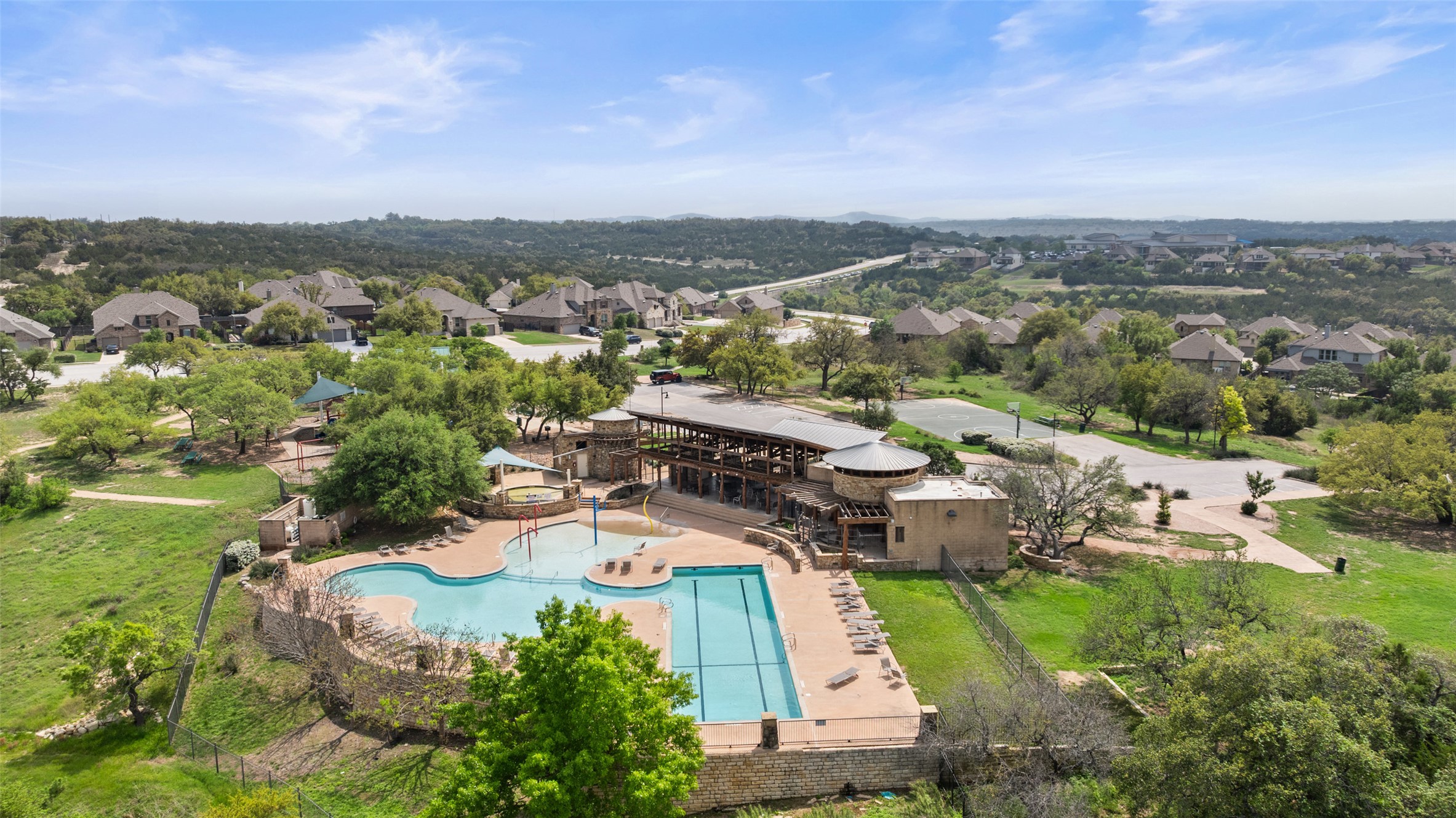 5528 Wild Foxglove Road Spicewood, TX 78669 - Photo 37 of 38 Community amenity center featuring a swimming pool with integrated water features, a lap pool, and a structured clubhouse building with covered patios