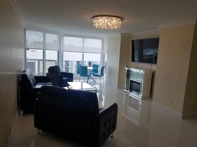 a living room with furniture a flat screen tv and a floor to ceiling window