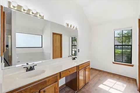 an empty room with wooden floor chandelier fan and windows