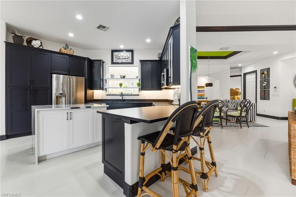 19979 Markward Crossing Estero, FL 33928 - Photo 12 of 36 a kitchen with stainless steel appliances kitchen island granite countertop a refrigerator a stove a sink a dining table and chairs with wooden floor
