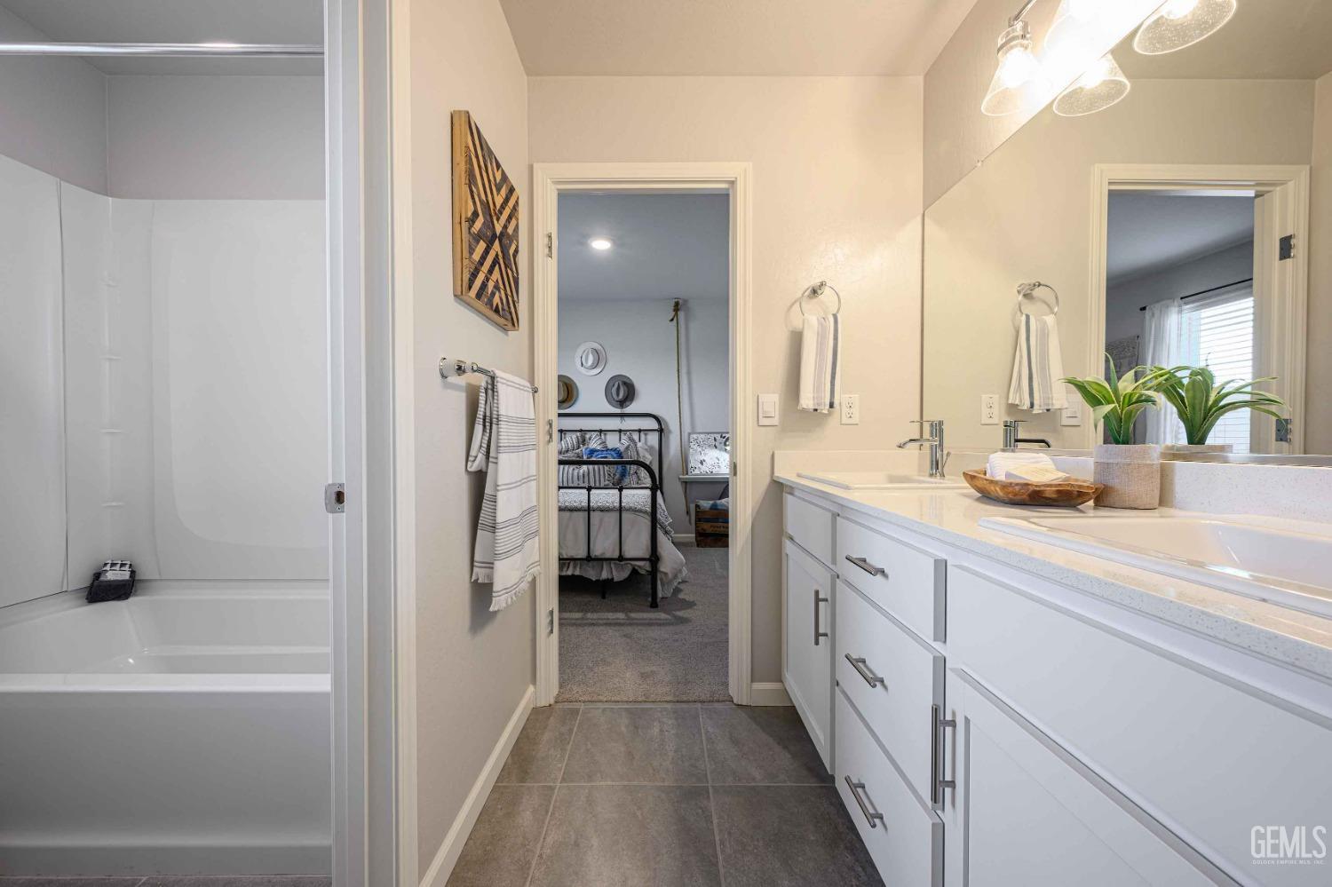Undisclosed Address Bakersfield, CA 93313 - Photo 15 of 21 a spacious bathroom with a double vanity sink a mirror and a bathtub