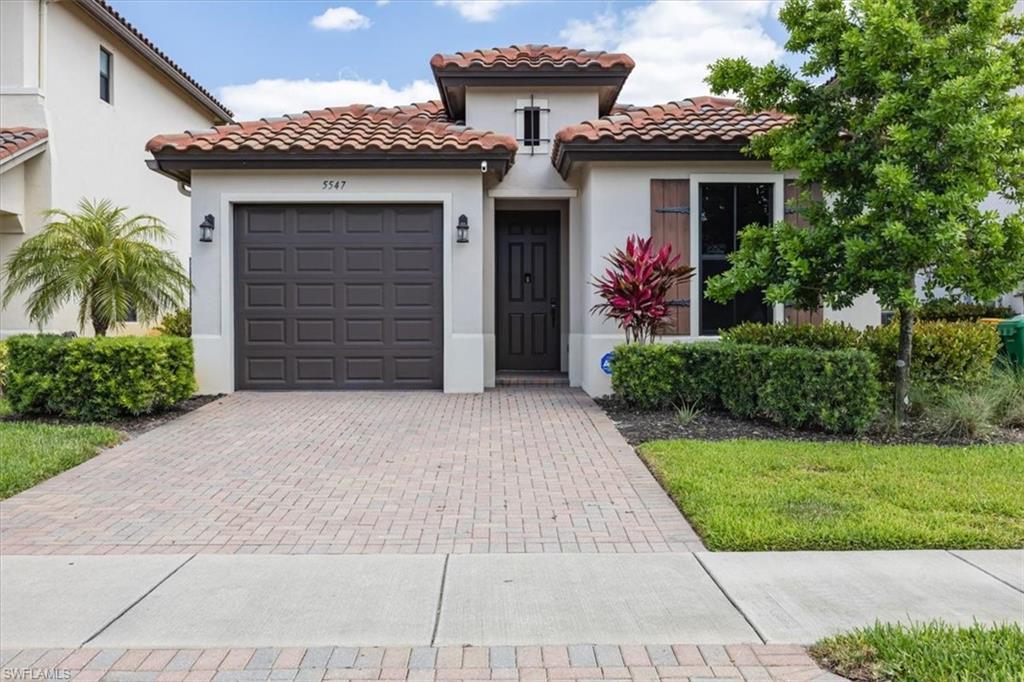 Mediterranean / spanish-style home featuring stucco siding, decorative driveway, a tiled roof, and a garage