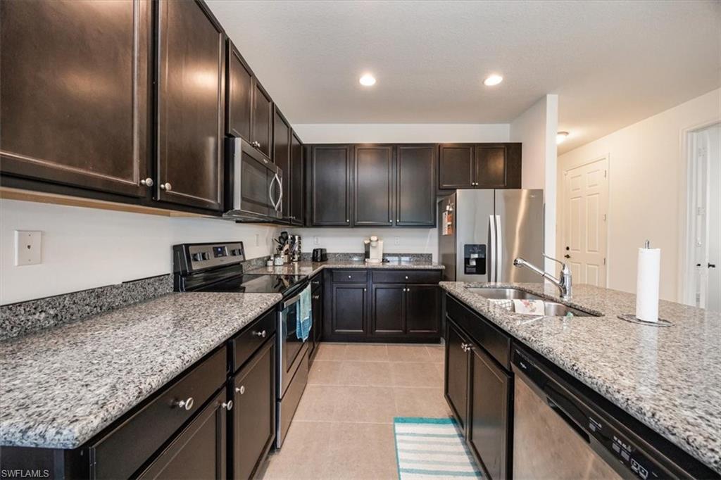 5547 Useppa Drive Ave Maria, FL 34142 - Photo 8 of 33 Kitchen with a sink, light stone countertops, stainless steel appliances, and light tile patterned flooring