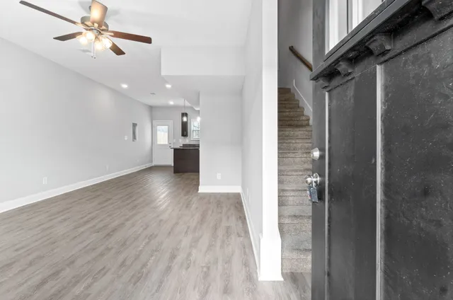 a view of a hallway with wooden floor and chandelier fan