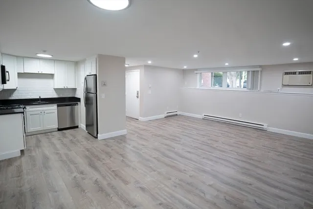 an empty room with wooden floor and stainless steel appliances