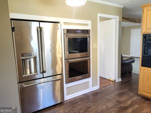 a view of a kitchen with a refrigerator a stove top oven and hallway
