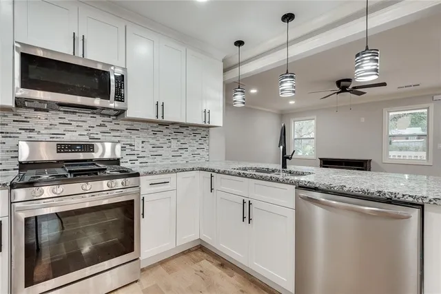 a kitchen with stainless steel appliances granite countertop a stove microwave and a sink