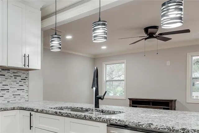 a view of a kitchen with granite countertop cabinets a sink and a chandelier