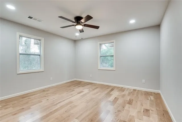 an empty room with windows and fan