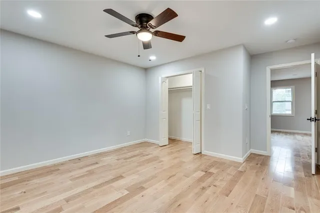 an empty room with wooden floor and a ceiling fan