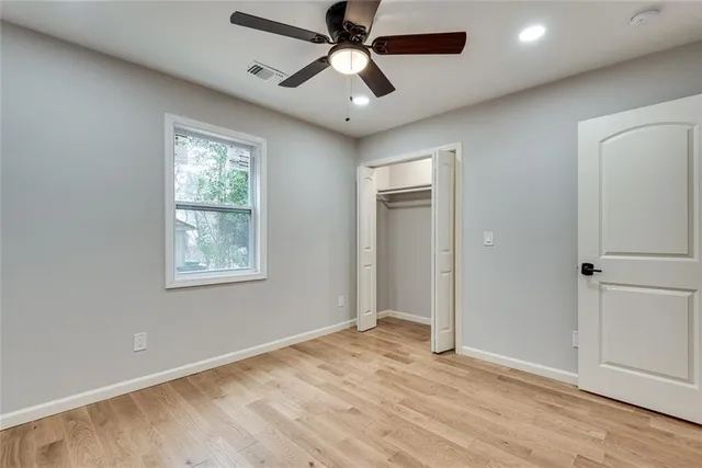 a view of empty room with wooden floor and fan