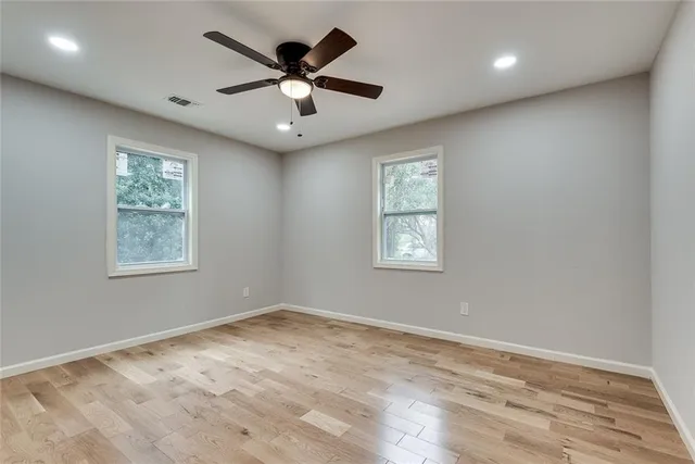 an empty room with wooden floor and windows