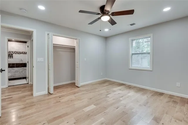 an empty room with wooden floor and a ceiling fan
