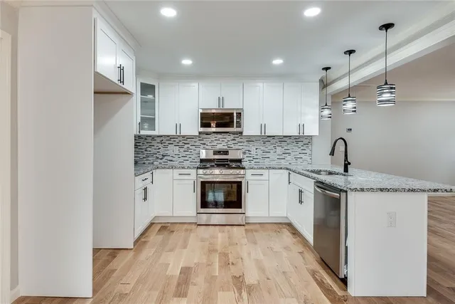 a kitchen with granite countertop a stove top oven a sink and a refrigerator
