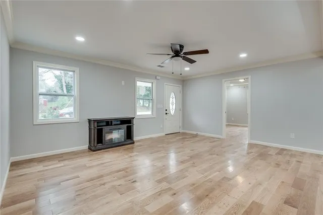 a view of empty room with wooden floor and fan