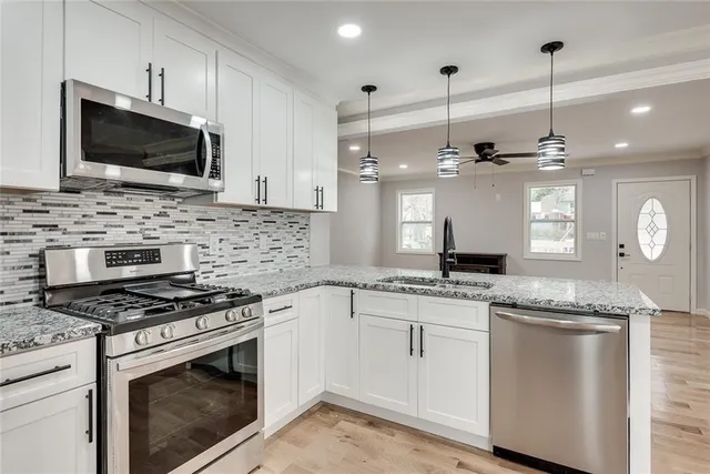 a kitchen with stainless steel appliances granite countertop a stove microwave and a sink