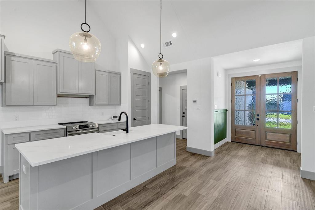 2029 Rattler Way Tolar, TX 76476 - Photo 9 of 28 a kitchen with stainless steel appliances a sink dishwasher a refrigerator a stove and white cabinets with wooden floor