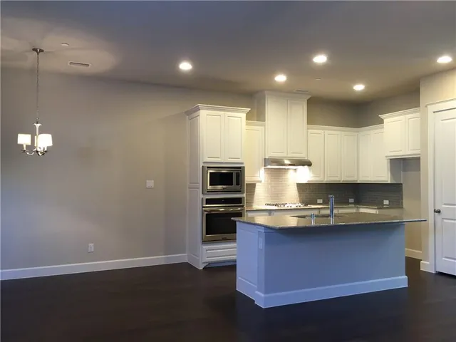 a kitchen with kitchen island granite countertop wooden cabinets and stainless steel appliances