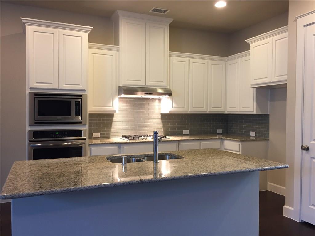 1017 Water Street Carrollton, TX 75007 - Photo 6 of 21 a kitchen with kitchen island granite countertop a sink a stove and cabinets