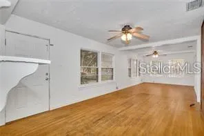 a view of an empty room with window and wooden floor
