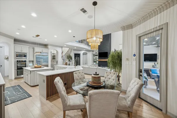 a dining room with stainless steel appliances granite countertop a table chairs and a kitchen view