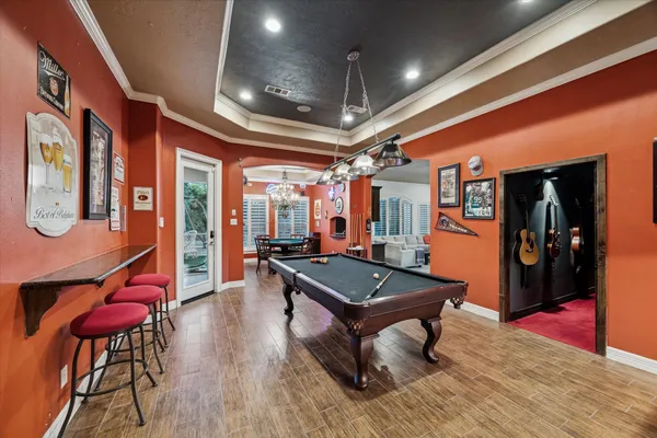 a room with furniture pool table gym equipment wooden floor and windows