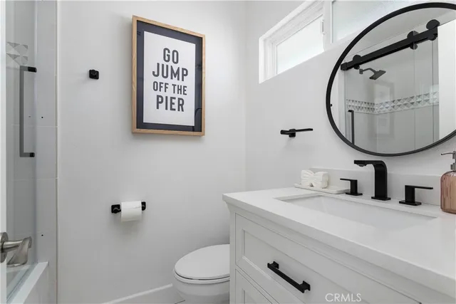 a bathroom with a toilet sink vanity and mirror