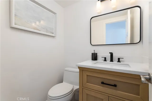 a bathroom with a toilet sink vanity and mirror