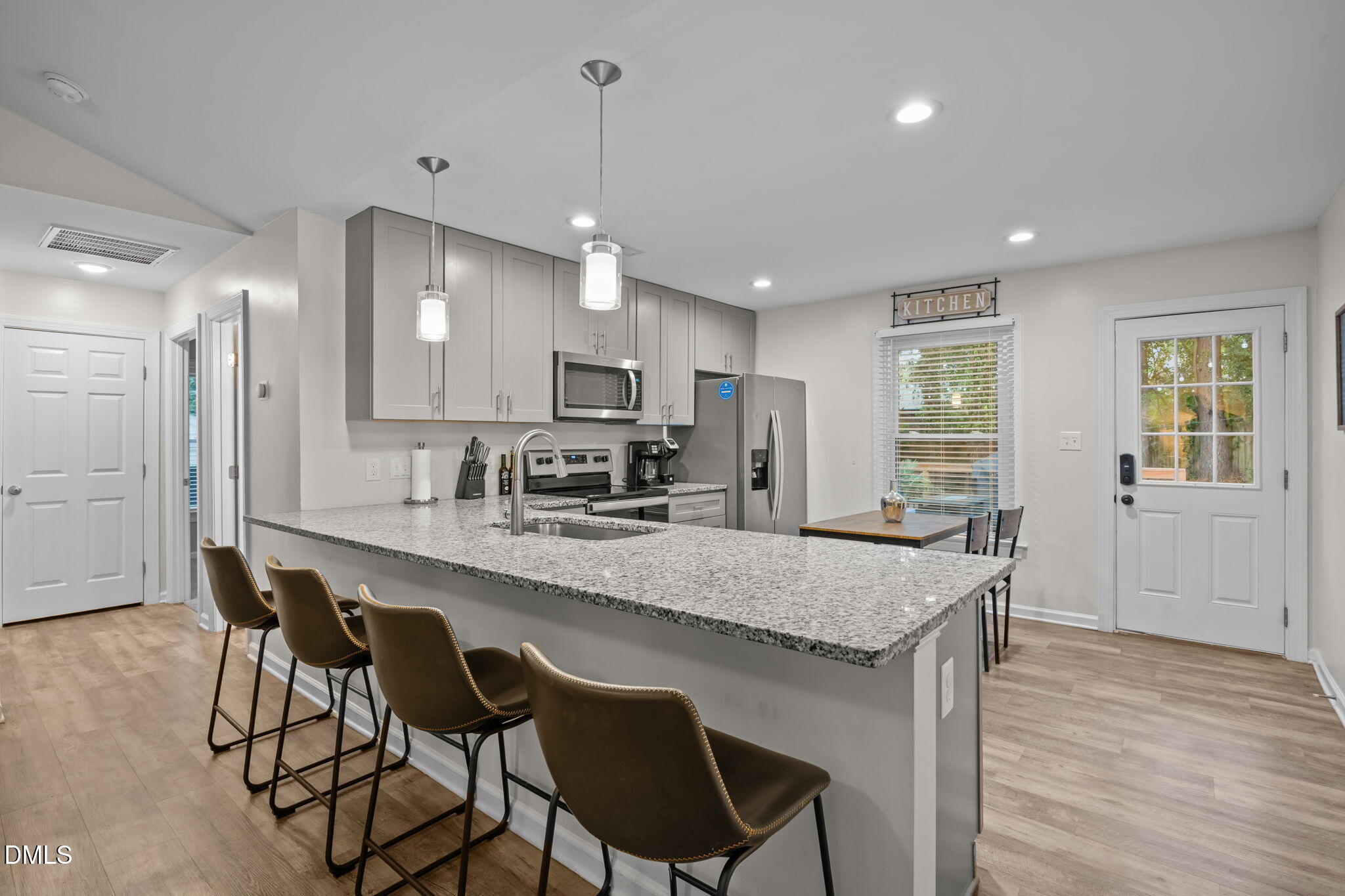 2752 Milburnie Road Raleigh, NC 27610 - Photo 12 of 54 a kitchen with granite countertop a table chairs microwave and cabinets