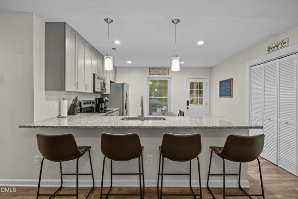 a kitchen with granite countertop a table chairs microwave and cabinets