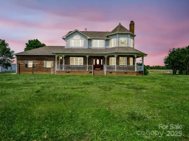 a view of a house with a big yard and large trees