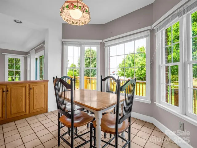 a view of a dining room with furniture a chandelier and large windows