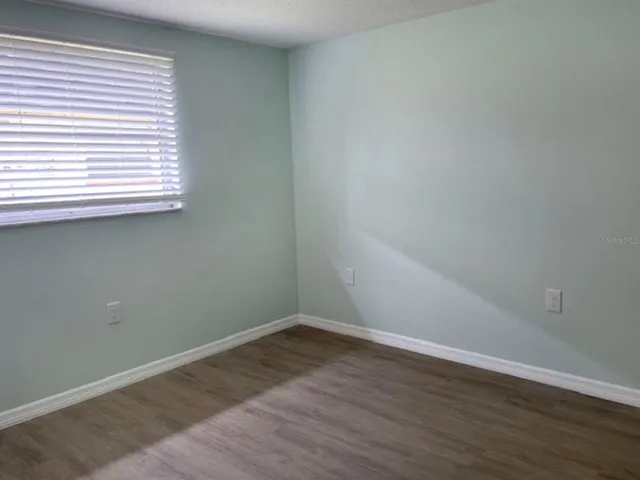 an empty room with wooden floor and a window