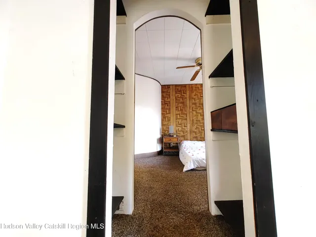 a bedroom with a bed and a large mirror next to a window