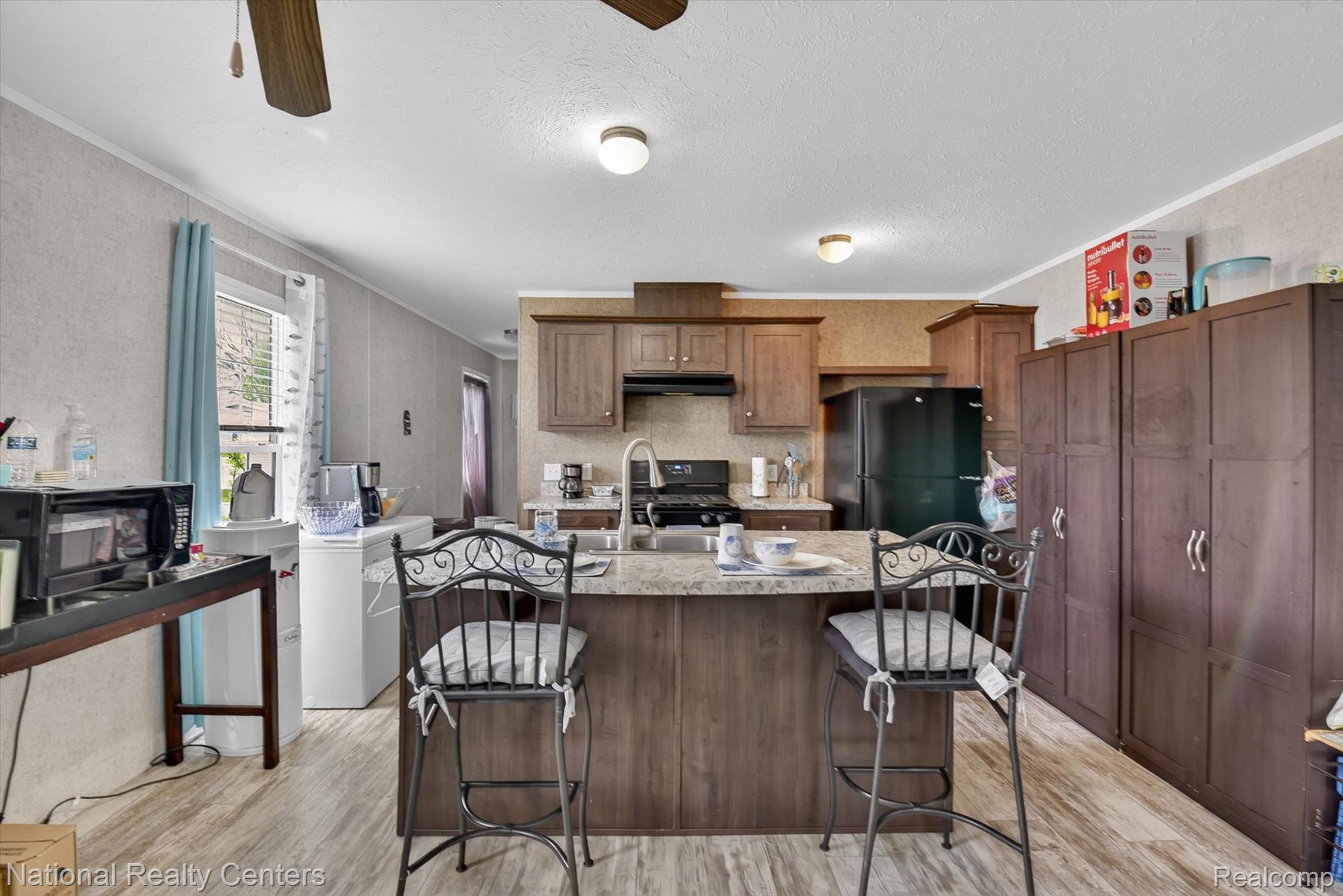 2735 South Wagner Road, Unit 103 Ann Arbor, MI 48103 - Photo 5 of 20 Kitchen with a kitchen bar, a ceiling fan, crown molding, a textured wall, and light wood-style floors