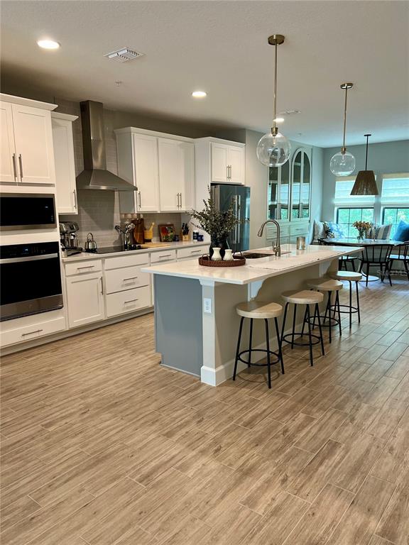 1266 Spotted Sandpiper Loop Winter Springs, FL 32708 - Photo 5 of 21 a kitchen with stainless steel appliances granite countertop a stove top oven a sink dishwasher a dining table and chairs with wooden floor