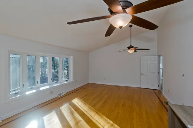 a view of an empty room with a window and wooden floor