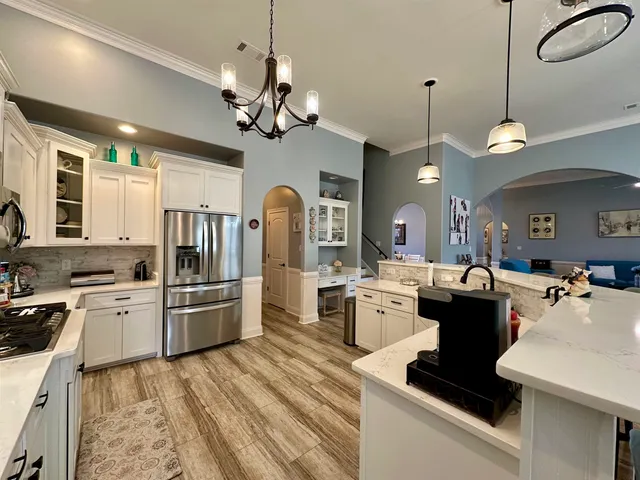 a large kitchen with stainless steel appliances a stove center island a dining table and chairs