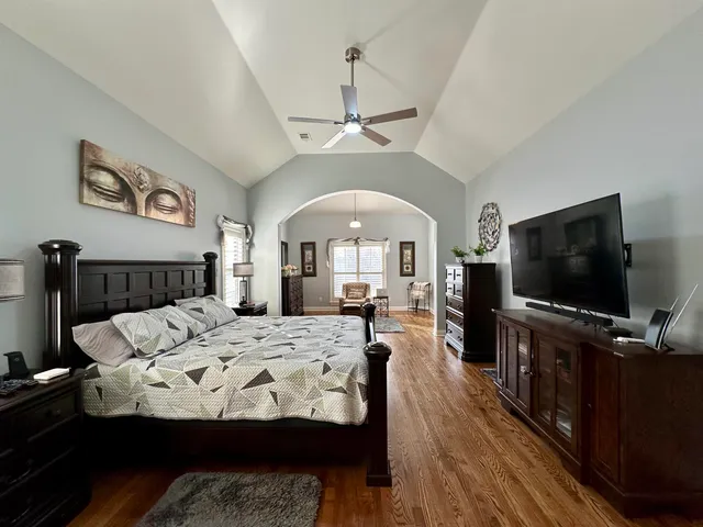 a spacious bedroom with a bed a dresser and windows