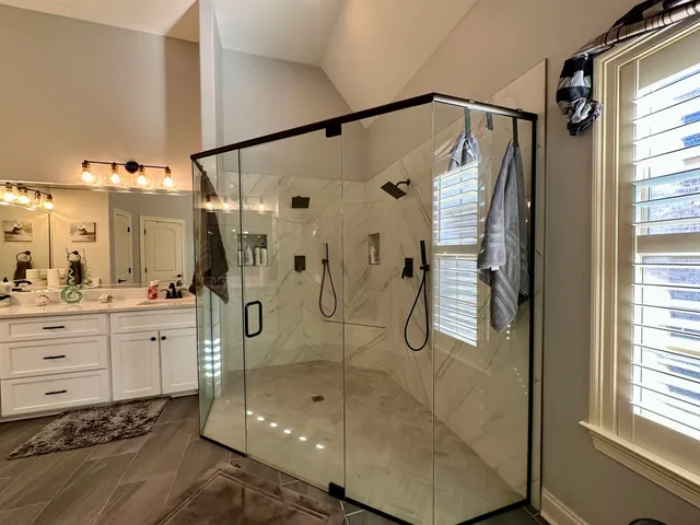 a bathroom with a glass shower door a bathtub a sink and a mirror