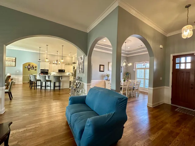 a living room with couches a dining table and chairs with wooden floor