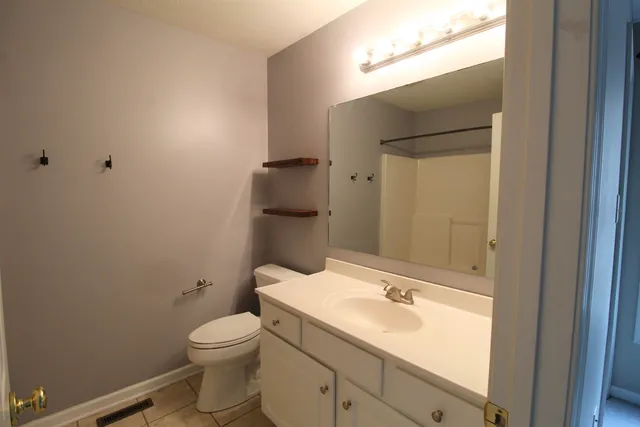 a bathroom with a granite countertop toilet a sink and a mirror