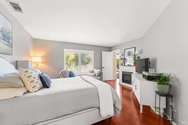 a bedroom with a bed a large window and wooden floor
