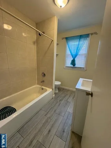a bathroom with a tub a sink and wooden floor