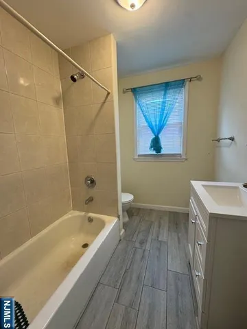 a bathroom with a tub a sink and wooden floor