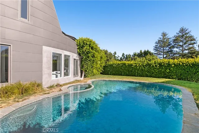 a view of pool with lawn chairs and plants