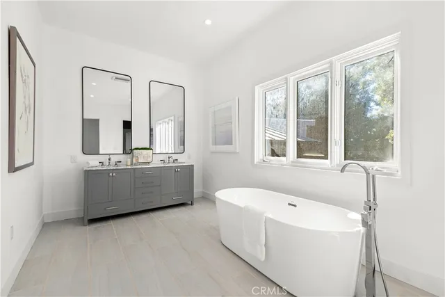 a bathroom with a tub a sink and a mirror