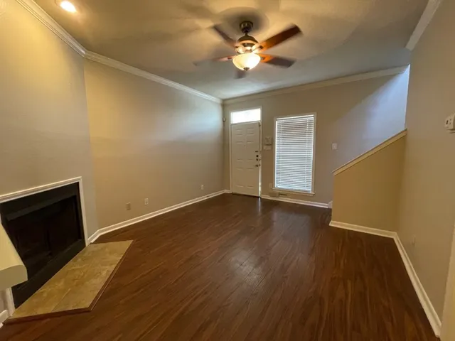 a view of an empty room with wooden floor and a ceiling fan