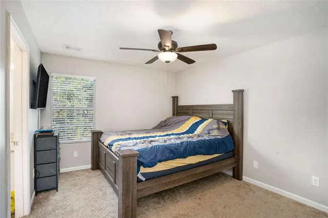 a bed sitting in a bedroom next to a window with a flat screen tv