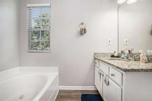 a bathroom with a granite countertop sink and a bathtub